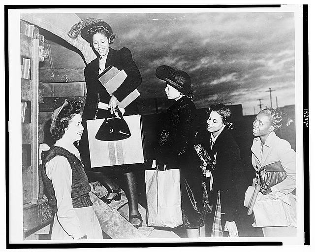[African American women climbing into Army truck, probably WAACs about to begin training]