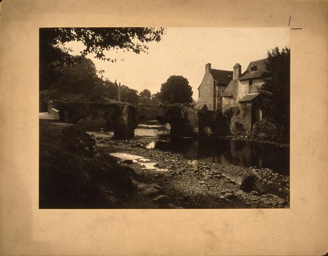 [View of a stone bridge, river and buildings in a village, probably in France]