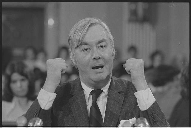 [Daniel Patrick Moynihan, head-and-shoulders portrait, speaking behind microphones, gesturing with his hands, probably at a meeting of the Senate Committee on Foreign Relations]