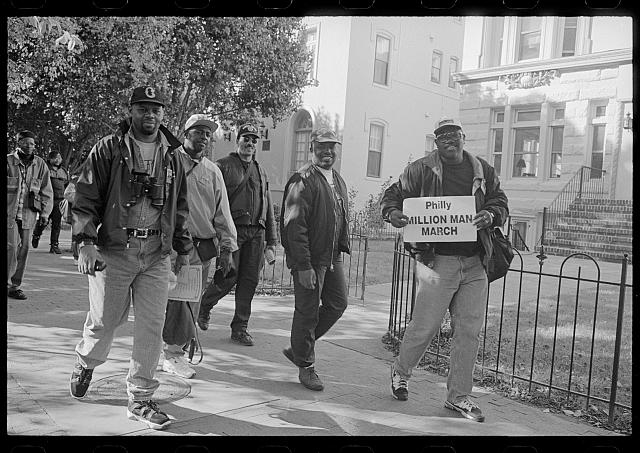 [African American men walking on a sidewalk, probably on Capitol Hill, during the Million Man March in Washington, D.C.]