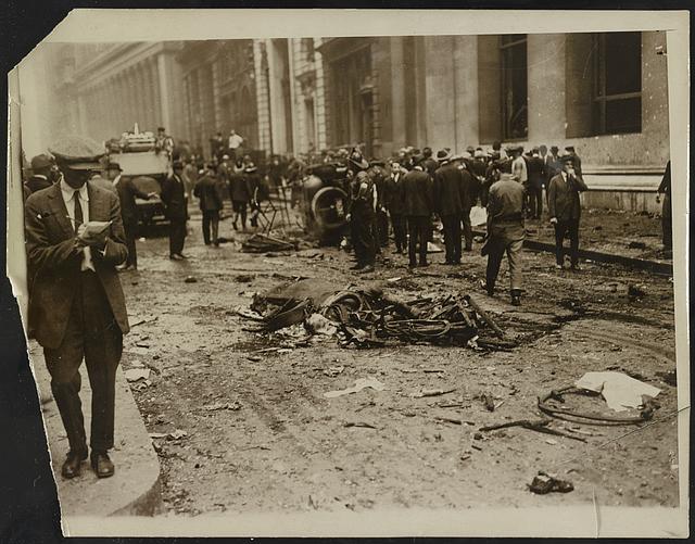 [Crowd gathered behind a dead horse after the Wall Street explosion in front of the offices of J.P. Morgan; man, probably a reporter, writes in a notebook in the foreground]