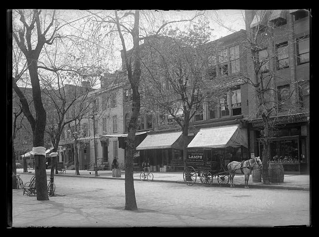 [View probably of G Street, N.W., South side, looking South from near 12th Street, a C.A. Muddiman & Co. electric and gas fixtures' horse and cart stands at the curb in front of the shops]