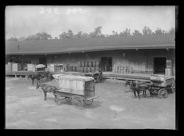 [View of S.W., block 386, probably D Street side of Baltimore & Potomac Railroad freight station between Maryland & D, 9th & 10th showing freight and horse-drawn carts in front of station]