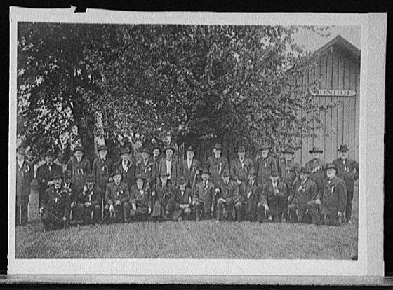 [Group of men, probably war veterans posed in front of building with Monroe on it]