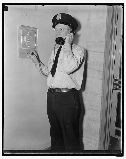 F.B.I. guard reports in. Washington, D.C., Aug 4. Officer Ray D. Buckingham using a plug-in telephone, which every guard carries as part of his regular equipment, reports to headquarters as he patrol his section of the 7 miles of corridors in the Department of Justice Building. The home of the G-Men is probably the most carefully guarded government building in the Capitol. The aces of the Guard Force are chosen to protect that part of the building which houses the records of Federal Bureau of Investigation, 8/4/37