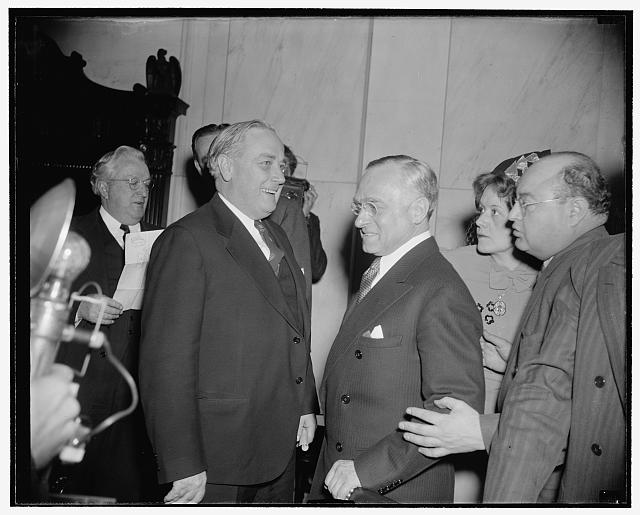 Frankfurter critic passes by. Washington, D.C., Jan. 12. Probably it was just a coincidence that Mrs. Elizabeth Dilling, right, anti- Communist author, was passing by as this picture of Prof. Felix Frankfurter talking to Senator Alexander Wiley of Wisconsin in the Senate Judiciary Subcommittee hearing room. Yesterday before the committee, Mrs. Dilling assailed the nomination of Frankfurter to the Supreme Court and denounced all liberals, including the Roosevelt family, 1/12/39