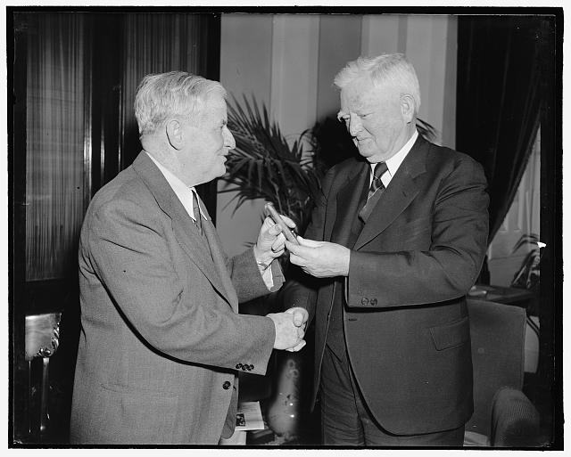 Vice President congratulates Senate press gallery head on 30 years of service. Washington, D.C., March 22. Rounding out 30 years of service in the Senate Press Gallery today, William J. Collins, present Superintendent, is congratulated by Vice President Garner and accepts one of the V.P.'s favorite cigars. Willie, as he is familiarly known, probably knows more newspapermen by sight than any other person in the country. 3-22-39