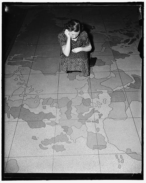 European situation spoils map on Post Office department floor. Washington, D.C., April 12. The huge map on the floor of the Post Office Department here is all out of kilter these days due to the aggression in Europe. Many are the embarrassing questions being asked officials about when Mr. Farley is going to do something about Ethiopia, Austria and Czechoslovakia. The answer so far has been - nothing. Probably the Post Office is waiting to see what will happen next on the continent. Miss Edna Strain is inspecting the damage done by the ambitious dictators. 4-12-39