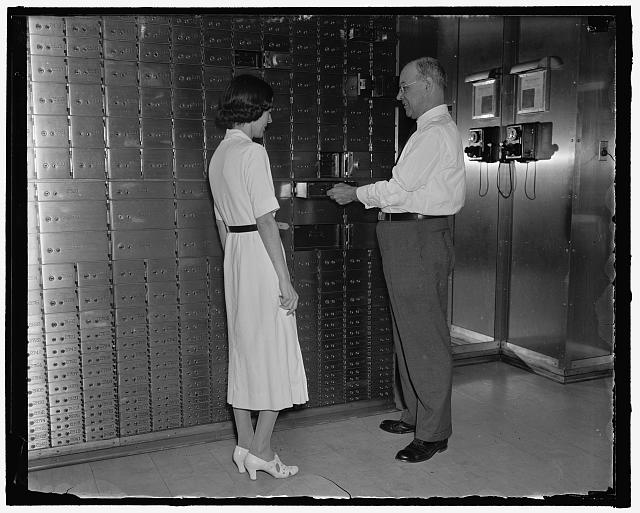 Former White House officer in new role. Washington, D.C., Sept. 9. For 36 years Lieut. Ernest M. "Larry" Seaman stood day after day at the door of the White House Executive offices and welcomed presidential callers. During this time "Larry" probably met more famous people than any other person in the world. But this past history for Seaman now as he retired a short time ago and accepted a post at a local bank in charge of safety deposit vaults. Prior to coming to the White House during the Roosevelt Administration he was for four years a member of the Metropolitan Police Force. Seaman is shown opening one of the boxes for Miss Katheryn Fout, 9/9/37
