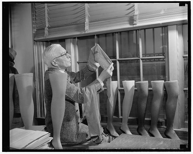Freezing of Japan's credits may popularize cotton stockings for milady. Washington, D.C., July 26. It appears that the U.S. Department of Agriculture's efforts to improve cotton stockings and thereby popularize the wearing of them as a means of disposing of surplus long-staple cotton, will bear fruit now that Japan's assets have been frozen in the U.S. Japan furnishes most of the silk used in the stockings manufactured in this country and at the present time, according to reports, there is only about two and a half month's supply left. Trade between the U.S. and Japan no doubt will be hard hit because of the difficulty of making payments. Nylon production is also slow so the ladies will probably be wearing cotton stockings by the end of the year or else go barelegged. In this picture, David H. Young, Agriculture Department fabric technician, is shown examining one of the cotton stockings which they are trying to popularize