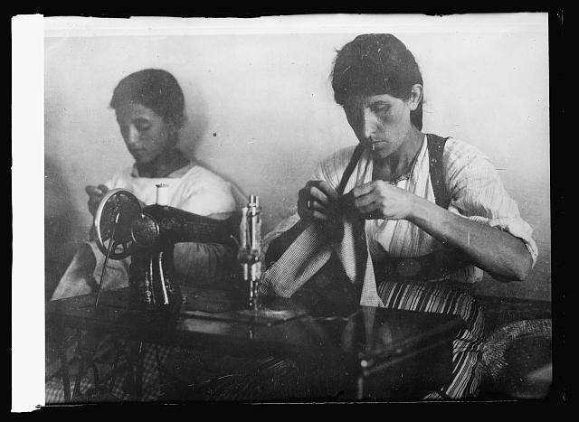 Something New in an Old, Old World. A close-up of two Albanian women at work on a modern American sewing machine. In this Balkan country, which is probably the least toouched by modern inventions of any nation in Europe, the women learned to sew on a machine for the first time in the workrooms established by the Red Cross. Sewing schools were set up in various parts of the country and women made the unfinished cloth sent from American into thousands of garments for the poor and destitute of their country. The workers, who were themselves in straightened circumstances, were paid in supplies, for which they were most grateful