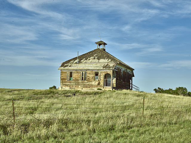 Abandoned one-room schoolhouse in a mostly abandoned town: Aroya, in Cheyenne County, Colorado. The name "Arroyo", the Spanish word for "gulch," appears on some older maps. Aroya, probably a corruption of the Spanish, originated in 1870 three miles west of the present site as a camp for Kansas-Pacific Railroad track-layers, but was moved to the present site because there was a better supply of water. The schoolhouse was in use until the early 1960s