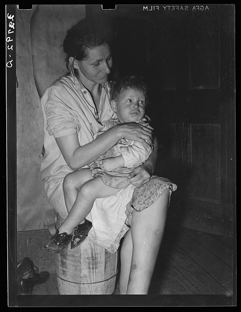 Mother and child. This woman, wife of an ex-farmer now living on relief, had pellagra in an advanced stage. She has had some treatment and shown great improvement but there were still evidences of mental disturbance.  She was the mother of twelve children. The child in her arms has malaria as have probably the entire family. Jefferson, Texas