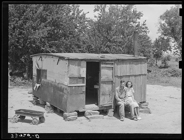 WPA (Works Progress/Work Projects Administration) worker and his wife sitting in front of their shack home on the Arkansas River near Webbers Falls, Oklahoma. This man said that last year he thought maybe he would be a little better off when he got the WPA work and had a small amount of cash coming in but that he was worse off now. "Last year I had a cow and some chickens and I had to sell my cow and eat my chickens. I get worse off every year"