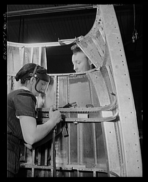 Two North American employees rivet the nacelle for a B-25 bomber. Woman and man. Women will probably be doing eighty percent of work at this plant next year. Now approximately twenty percent