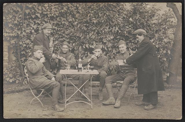 [Four unidentified soldiers in uniform drinking wine as two civilians hand them papers, probably in France]