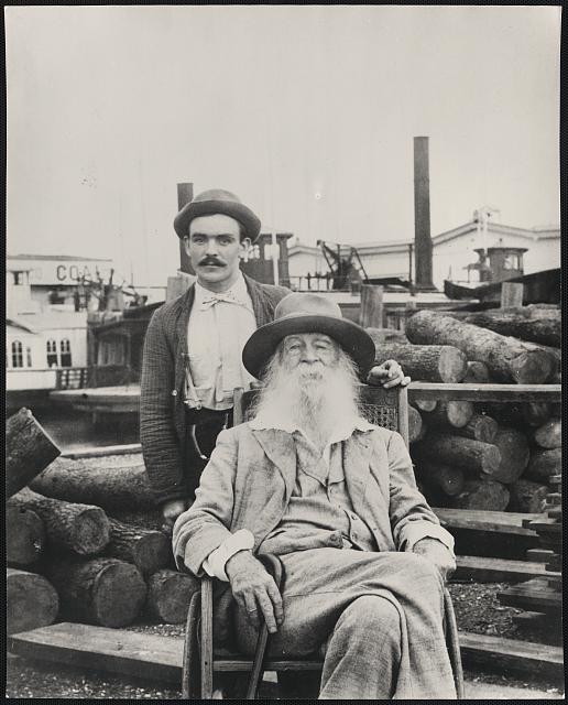 [Walt Whitman, three-quarter length portrait, seated, facing front, with his nurse Warren Fritzenger, standing, and a pile of logs behind him, on the wharf, probably near his Mickle Street house in Camden]