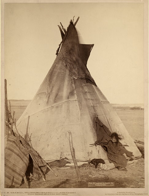 [A young Oglala girl sitting in front of a tipi, with a puppy beside her, probably on or near Pine Ridge Reservation]