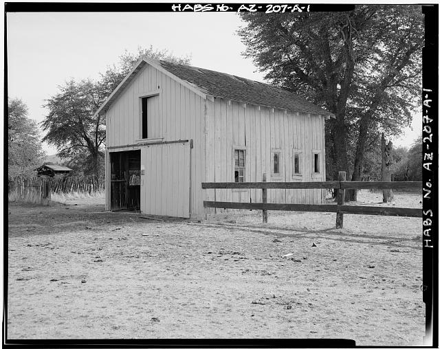 1.  BARN. VIEW LOOKING SOUTHEAST. EACH HORSE STALL HAS A SMALL WINDOW. THE 4/4 DOUBLE-HUNG WINDOW IS IN THE STORE ROOM. THE ROLLING DOOR WAS WIDENED, PROBABLY IN 1926, ELIMINATING THE ORIGINAL LOFT LADDER AT THE CORNER OF THE BUILDING. THE PUBLIC RESTROOM NEAR THE LEFT EDGE OF THE VIEW DOES NOT RELATE TO THE RANGER STATION. - Tonto Ranger Station, Barn, Forest Service Road 65 at Tonto Wash, Skull Valley, Yavapai County, AZ
