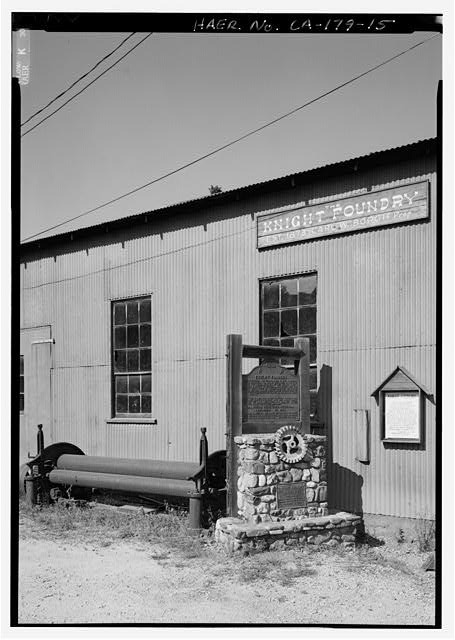 15.  SOUTHWEST CORNER OF MACHINE SHOP BUILDING. PLAQUES AND WATER IMPELLER. ROLLER PROBABLY FOR BENDING PIPE. - Knight Foundry, 13 Eureka Street, Sutter Creek, Amador County, CA