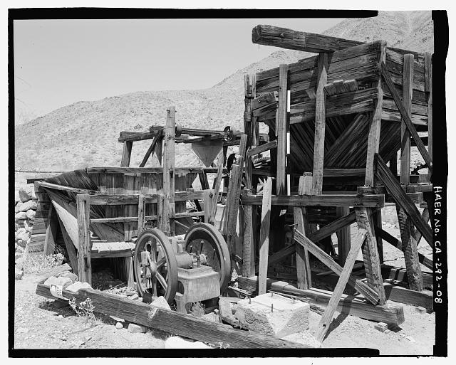 DETAIL VIEW OF ORE BINS AND JAW CRUSHER, LOOKING NORTHWEST FROM NEARBY THE ENGINE.  THE CONCRETE MACHINE PAD TO THE RIGHT OF THE CRUSHER PROBABLY HELD THE ENGINE THAT DROVE THE CRUSHER. - Gold Hill Mill, Warm Spring Canyon Road, Death Valley Junction, Inyo County, CA