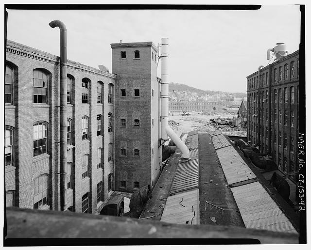 42.  VIEW EAST OF PLASTIC STACK (PROBABLY PVC) WHICH VENTED FUMES FROM THE DIPPING OPERATIONS IN BUILDING 49A; BUILDING 49 IS AT THE LEFT OF THE PHOTOGRAPH - Scovill Brass Works, 59 Mill Street, Waterbury, New Haven County, CT