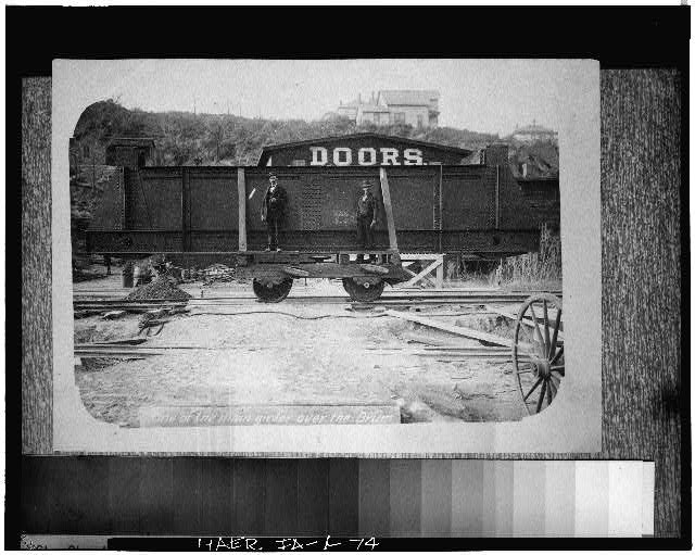 74.  CENTER GIRDER SECTION FOR THE BOTTOM CHORD OF THE IOWA SWING SPAN LOADED ON A DOLLY READY TO BE ROLLED OUT TO THE BRIDGE TO BE PLACER ON THE DRUM. PROBABLY TAKEN SEPTEMBER 7, 1895. - Pacific Shortline Bridge, U.S. Route 20,spanning Missouri River, Sioux City, Woodbury County, IA