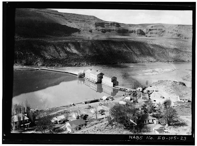 23.  VIEW TAKEN OF VILLAGE, DAM, AND POWER HOUSE AROUND 1945. CAMERA IS PROBABLY ON ROAD LEADING INTO VILLAGE AND FACES SOUTHWEST. CLUB HOUSE IS AT LOWER LEFT, WITH COTTAGES 361, 362, AND 363 TO THE RIGHT OF IT ON THE SAME SIDE OF THE ROAD. COTTAGE 231 SHOWS WASHING ON THE CLOTHESLINE. COTTAGE 101 AT LOWER RIGHT. - Swan Falls Village, Snake River, Kuna, Ada County, ID