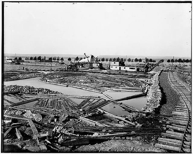 11.  Photocopied August 1978. INTAKE LOOKING NORTH AT UPPER INTAKE COFFER DAM, OCTOBER 10, 1900. ONE OF THE HUBBELL COMPANY DREDGES IS AT WORK IN THE CENTER OF THE ILLUSTRATION, THE TIMBER FLOATING AROUND WAS PROBABLY FOR USE IN THE CONSTRUCTION OF SIDE WALL RETAINING CRIBS. ONE OF THESE IS BEING CONSTRUCTED JUST TO THE LEFT AND TOWARDS THE VIEWER FROM THE DREDGES. (87) - Michigan Lake Superior Power Company, Portage Street, Sault Ste. Marie, Chippewa County, MI