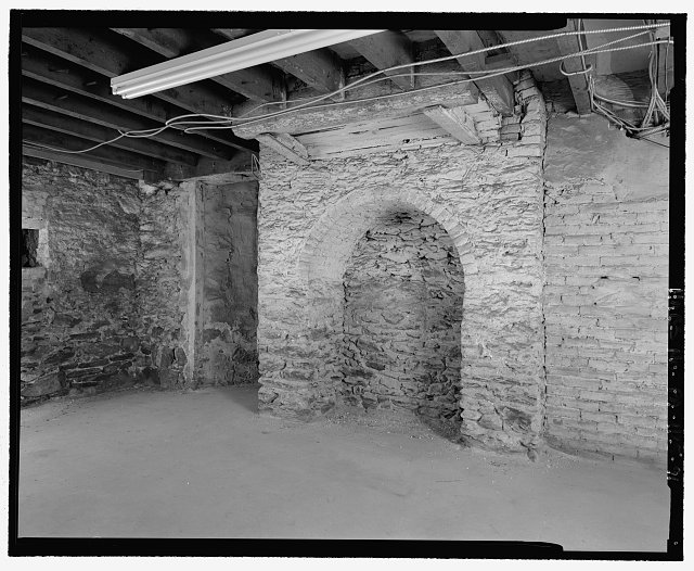 DETAIL VIEW, WEST WALL OF THE WESTERN STOREROOM. THE MASONRY HEARTH SUPPORT AND RELIEVING ARCH FOR A CHIMNEY MASS PROBABLY NEVER FUNCTIONED AS ENVISIONED, RATHER THEY ARE LIKELY A REMNANT OF A BUILDING SCHEME ABANDONED DURING THE HOUSE&#146;S INITIAL CONSTRUCTION - The Woodlands, 4000 Woodlands Avenue, Philadelphia, Philadelphia County, PA