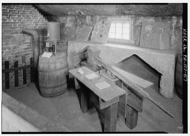 57.  ORIGINAL TILE PRESS AND EXPERIMENTAL DENTAL KILN, SECOND FLOOR, NORTH WING, HENRY MERCER USED THE KILN FOR HIS EARLIEST GLAZE TESTS. THE PRESS WAS DESIGNED TO BE USED WITH METAL CASED MOLDS. SINCE ONLY THE EARLIEST TILE DESIGNS ARE IN METAL CASES. THIS TECHNIQUE WAS PROBABLY DISCONTINUED. THIS PRESS WAS, THEREFORE, PROBABLY NOT USED EXTENSIVELY AT THIS SITE. THE UPPER PART OF GLAZE KILN No. 2 IS AT THE LEFT REAR. - Moravian Pottery & Tile Works, Southwest side of State Route 313 (Swamp Road), Northwest of East Court Street, Doylestown, Bucks County, PA