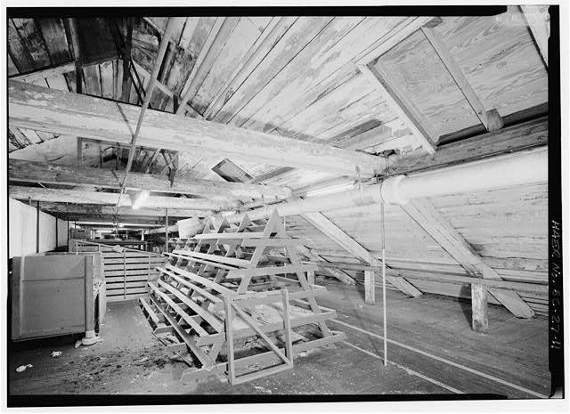 11.  INTERIOR OF ATTIC, VIEW FROM SOUTH END LOOKING AT ROOF STRUCTURE ON EAST SIDE OF BUILDING. NOTE HEAVY TIMBER TRUSS SYSTEM WITH THIN, VERTICAL METAL SUPPORTS. THESE SUPPORTS WERE PROBABLY ADDED AFTER ALTERATIONS ON THE LOWER FLOORS IN THE LATE 1930s. THE PEELING PAINT ON THE TRUSS TIMBERS AND BEADED HORIZONTAL PANELING FURTHER INDICATES THAT THIS SPACE WAS FINISHED FOR USE AS A PRODUCTION AREA. - Graniteville Mill, Marshall Street, Graniteville, Aiken County, SC